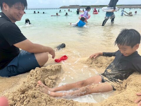 海で遊ぶ社員とその子ども
